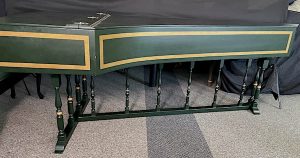 Image of a green harpsichord with closed lid. The case and lid are accented with gold boxes.