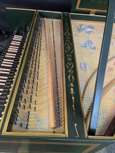 Detail of harpsichord tuning pegs, keyboard and soundboard painting.