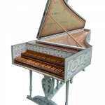 Image of a painted harpsichord with two manual keyboards and open lid. The case is painted in arabesque decorative designs and the legs of the stand are turned.